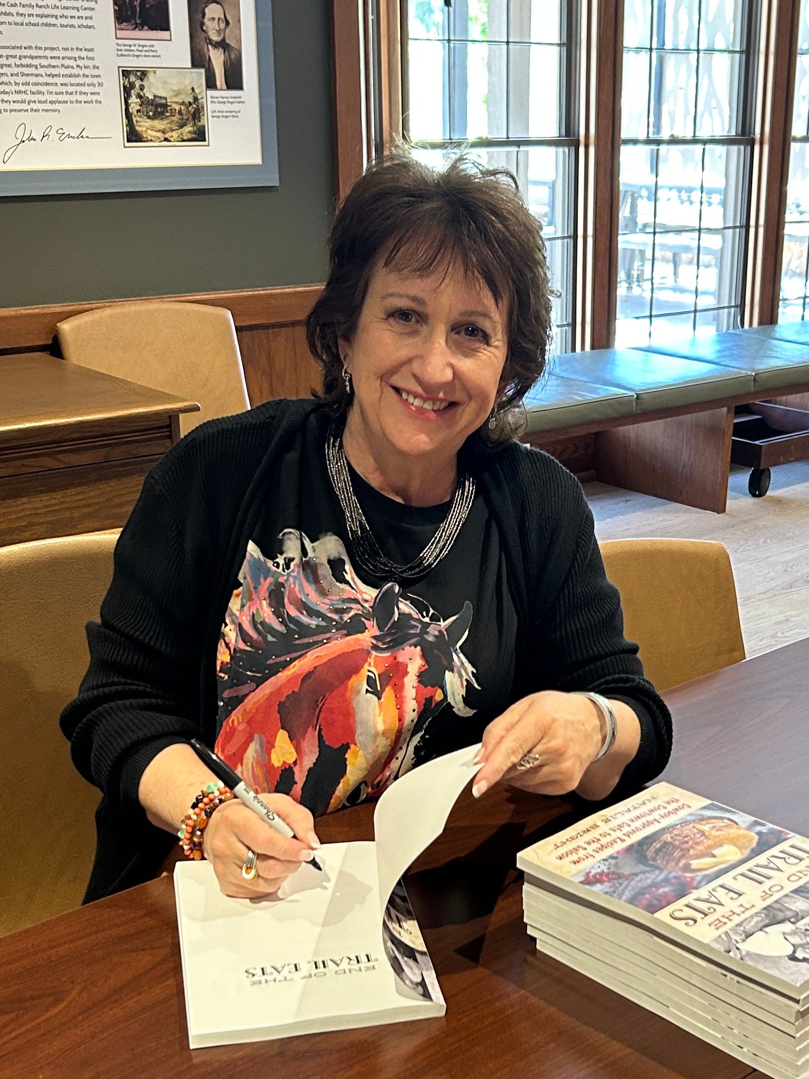 Natalie sitting at a table signing cookbooks