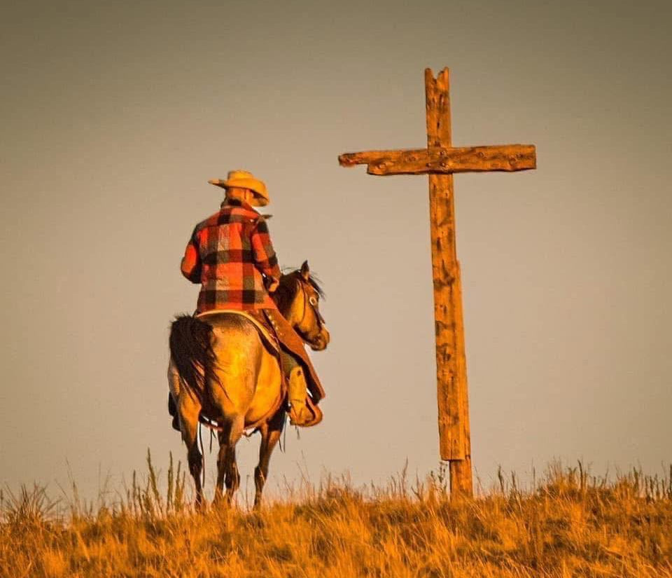 photo of cowboy horseback at a wooden cross by Michael Pintar